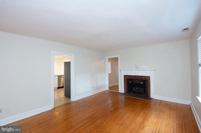 unfurnished living room with hardwood / wood-style floors and a brick fireplace