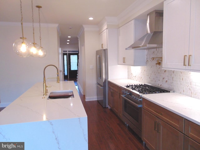 kitchen with pendant lighting, sink, wall chimney exhaust hood, white cabinetry, and high quality appliances