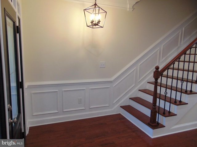 stairway with an inviting chandelier and wood-type flooring