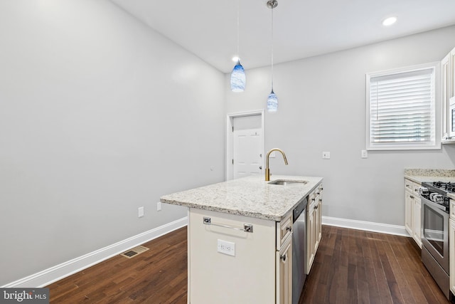 kitchen with dark hardwood / wood-style floors, sink, hanging light fixtures, stainless steel appliances, and a center island with sink