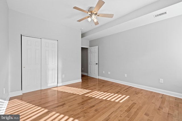 unfurnished bedroom with ceiling fan, a closet, and hardwood / wood-style floors