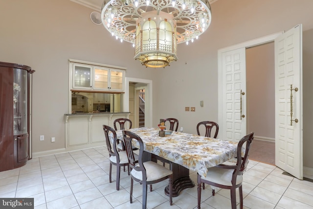 tiled dining area featuring crown molding, a high ceiling, and a chandelier