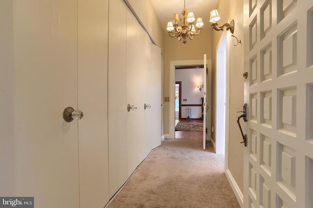 hall featuring light carpet and an inviting chandelier