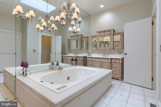 bathroom with an inviting chandelier, vanity, and a tub