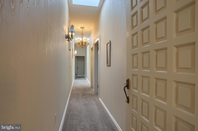 corridor with an inviting chandelier, a skylight, and light colored carpet