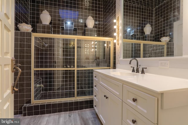 bathroom featuring walk in shower, hardwood / wood-style flooring, vanity, and tile walls