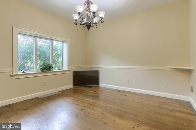 unfurnished room with hardwood / wood-style floors and a chandelier