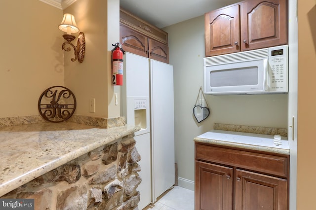 interior space with white appliances, ornamental molding, light stone countertops, and light tile patterned flooring