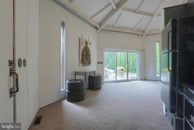 interior space featuring carpet floors and lofted ceiling with beams