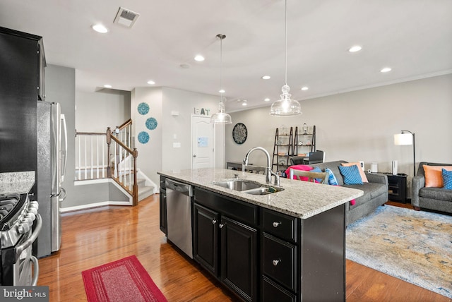 41930 Cushendall Ter, Aldie, VA 20105 - kitchen featuring appliances with stainless steel finishes, a sink, dark cabinetry, open floor plan, and an island with sink