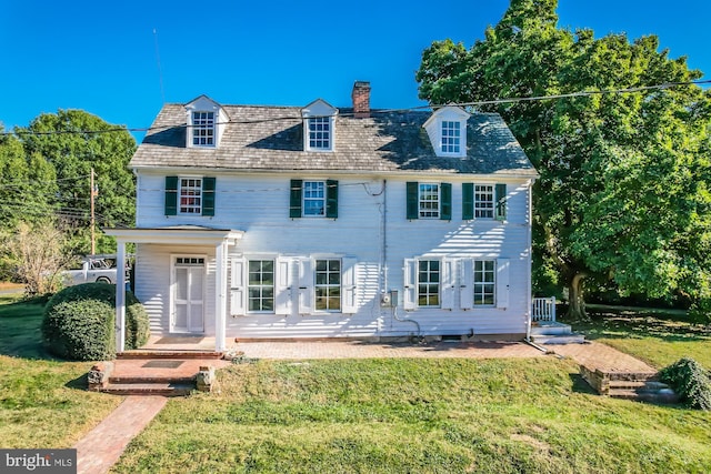 colonial home with a front lawn and a chimney