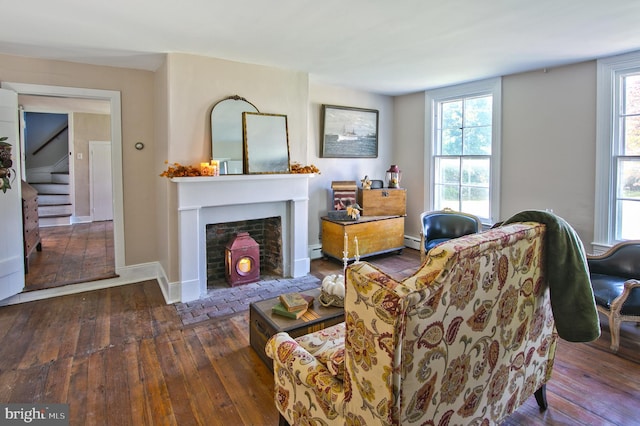 living room with dark wood-type flooring, baseboard heating, and plenty of natural light