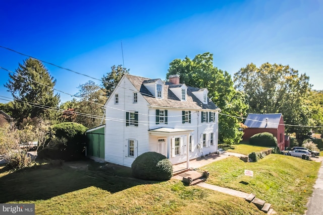 view of front of home featuring french doors, a balcony, and a front lawn