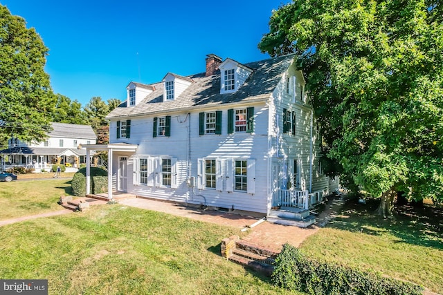 rear view of property featuring a yard and a chimney