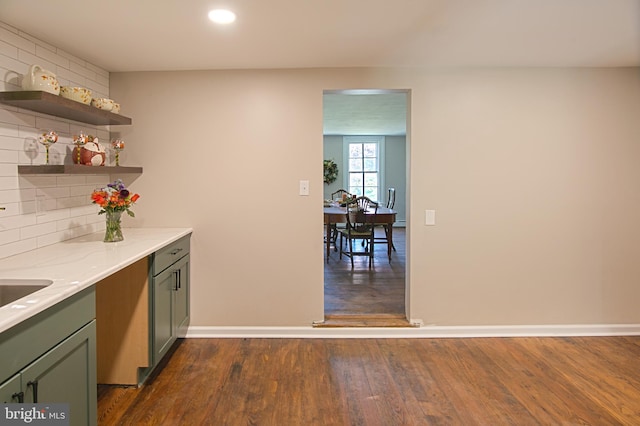 kitchen with light stone counters, backsplash, and dark hardwood / wood-style flooring