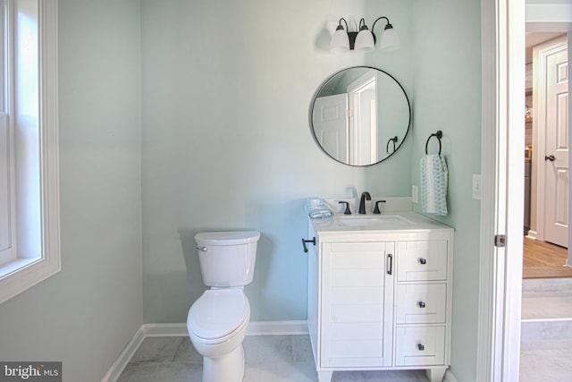 bathroom featuring a healthy amount of sunlight, vanity, toilet, and tile patterned floors