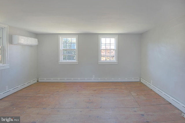 empty room featuring light hardwood / wood-style floors, baseboard heating, and an AC wall unit