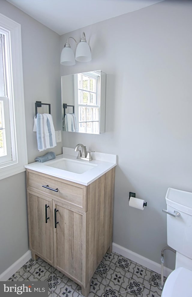 bathroom with toilet, vanity, and tile patterned floors