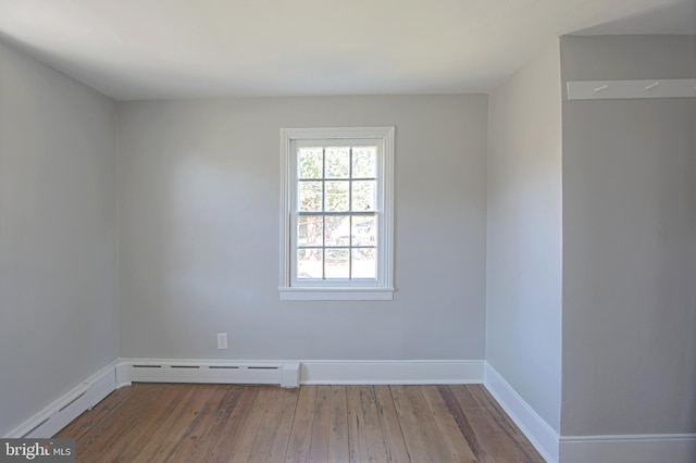 unfurnished room featuring hardwood / wood-style floors and a baseboard radiator