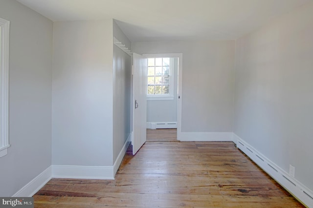 unfurnished room featuring a baseboard heating unit and light wood-type flooring