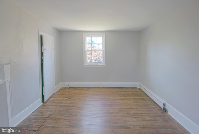 spare room featuring baseboard heating and hardwood / wood-style floors