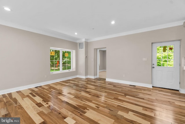 unfurnished room with a wealth of natural light, crown molding, and light wood-type flooring