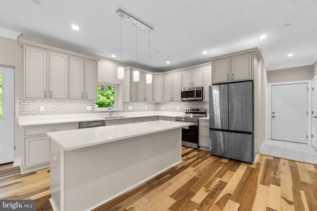 kitchen featuring pendant lighting, appliances with stainless steel finishes, a center island, plenty of natural light, and light wood-type flooring