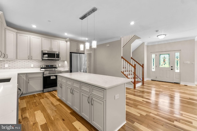 kitchen featuring pendant lighting, a kitchen island, light stone countertops, appliances with stainless steel finishes, and light hardwood / wood-style floors