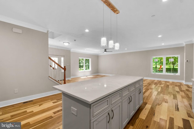 kitchen with decorative light fixtures, light wood-type flooring, gray cabinets, and crown molding