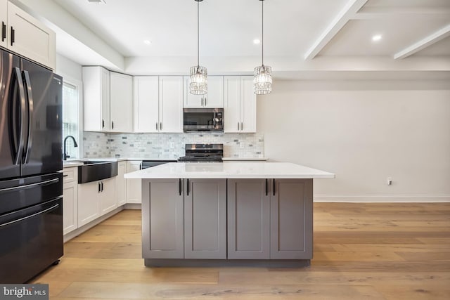 kitchen with white cabinets, appliances with stainless steel finishes, a kitchen island, and light hardwood / wood-style flooring