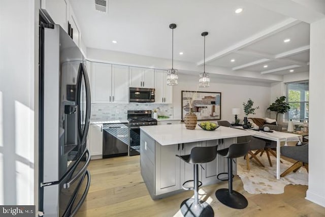 kitchen featuring appliances with stainless steel finishes, light hardwood / wood-style flooring, decorative light fixtures, and white cabinets