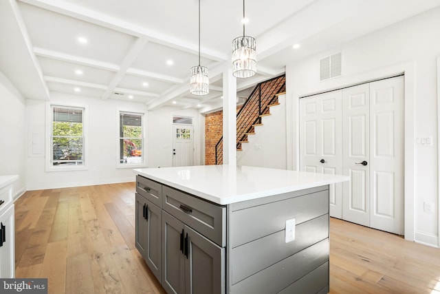 kitchen with hanging light fixtures, an inviting chandelier, light wood-type flooring, gray cabinets, and a kitchen island