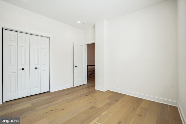 unfurnished bedroom with light wood-type flooring and a closet