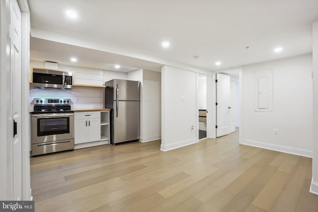 kitchen featuring white cabinets, light wood-type flooring, appliances with stainless steel finishes, electric panel, and butcher block countertops