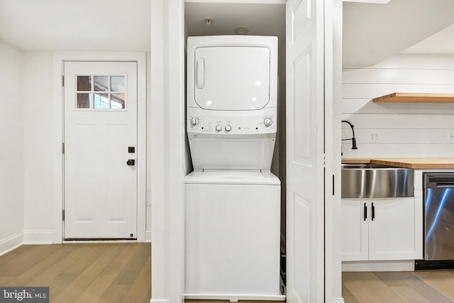 laundry room with light wood-type flooring, sink, and stacked washer and dryer