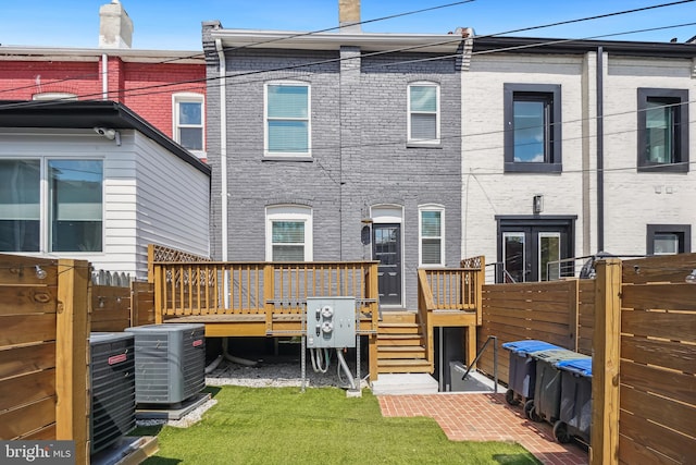 rear view of house with cooling unit, a yard, and a deck