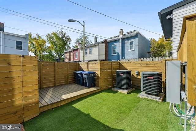 view of yard with central air condition unit and a wooden deck