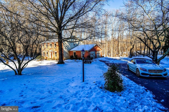 yard covered in snow featuring driveway and an attached garage