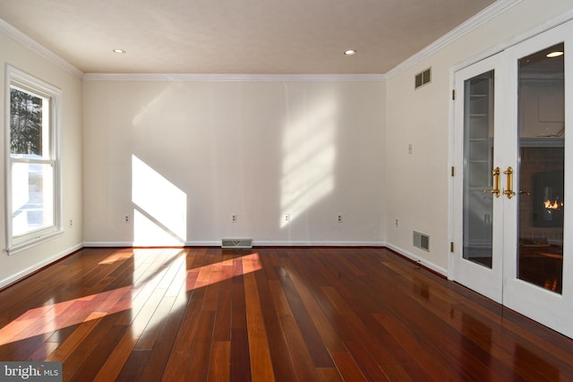 empty room featuring french doors, a brick fireplace, plenty of natural light, and crown molding