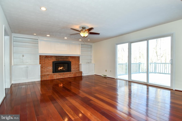 unfurnished living room featuring built in shelves, ceiling fan, a fireplace, and hardwood / wood-style flooring