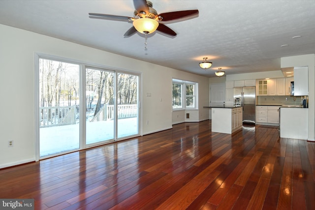 unfurnished living room featuring dark hardwood / wood-style floors, ceiling fan, and a textured ceiling