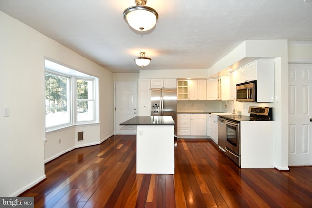 kitchen with white cabinetry, sink, a center island, dark wood-type flooring, and appliances with stainless steel finishes