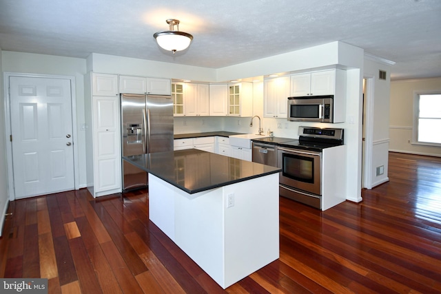 kitchen featuring sink, a kitchen island, dark hardwood / wood-style flooring, white cabinets, and appliances with stainless steel finishes