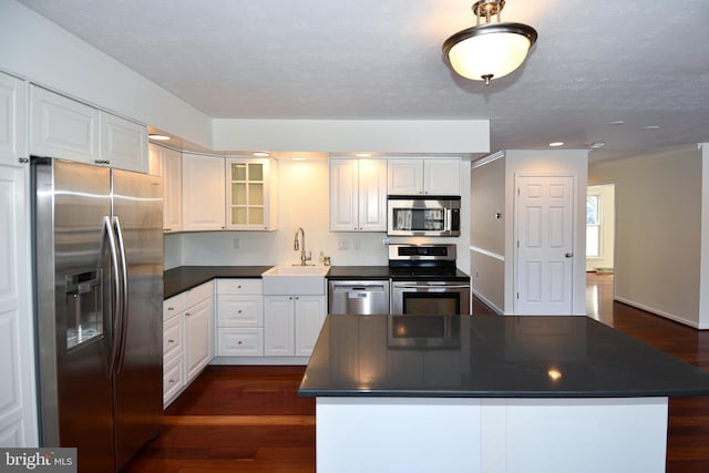 kitchen featuring stainless steel appliances, dark wood-type flooring, sink, white cabinets, and a center island