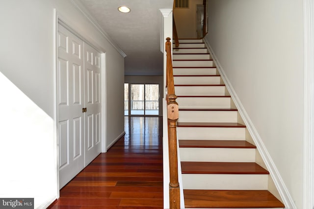 stairs featuring hardwood / wood-style floors and crown molding