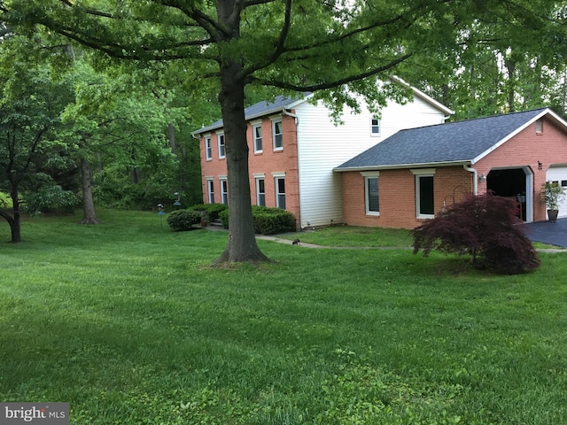 view of front facade featuring a garage, driveway, brick siding, and a front lawn