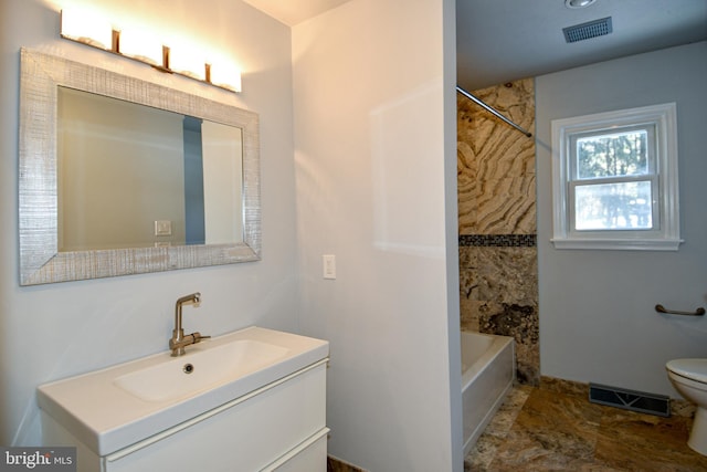 full bathroom featuring vanity, tiled shower / bath combo, and toilet