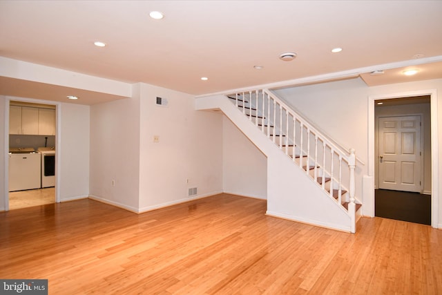 unfurnished living room featuring washer and dryer and light wood-type flooring