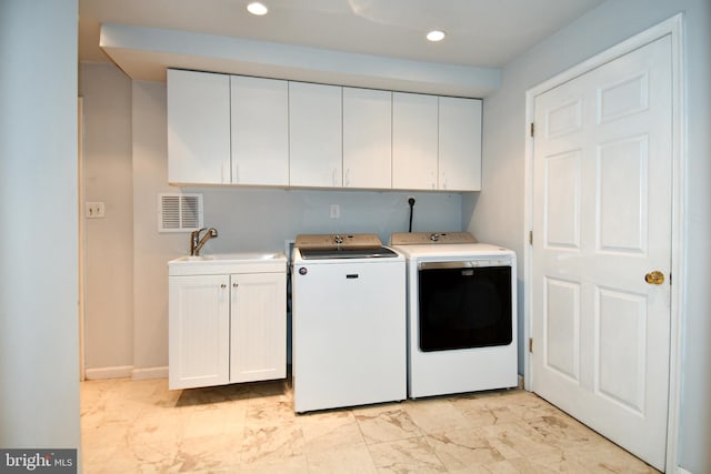 clothes washing area featuring washing machine and clothes dryer, sink, and cabinets