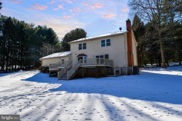 snow covered back of property featuring a wooden deck